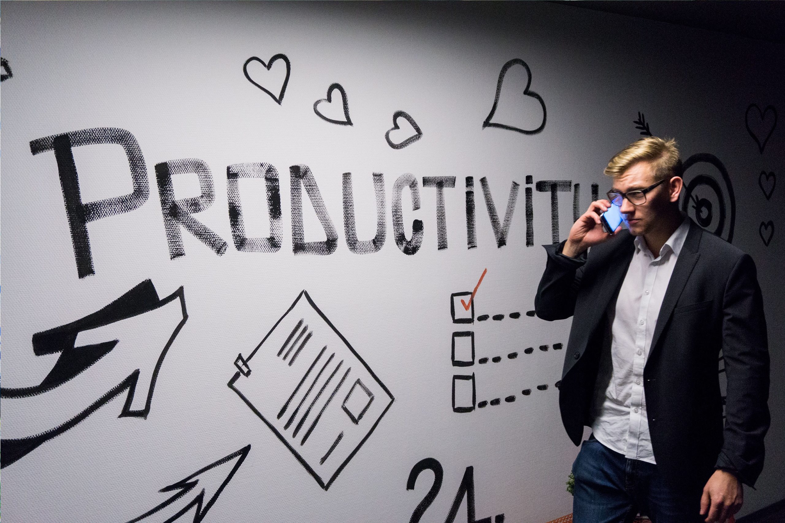 「PRODUCTIVITY」と描かれた壁の前で電話をする男性