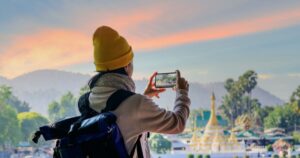 旅先の風景をスマートフォンで撮影する人の後ろ姿