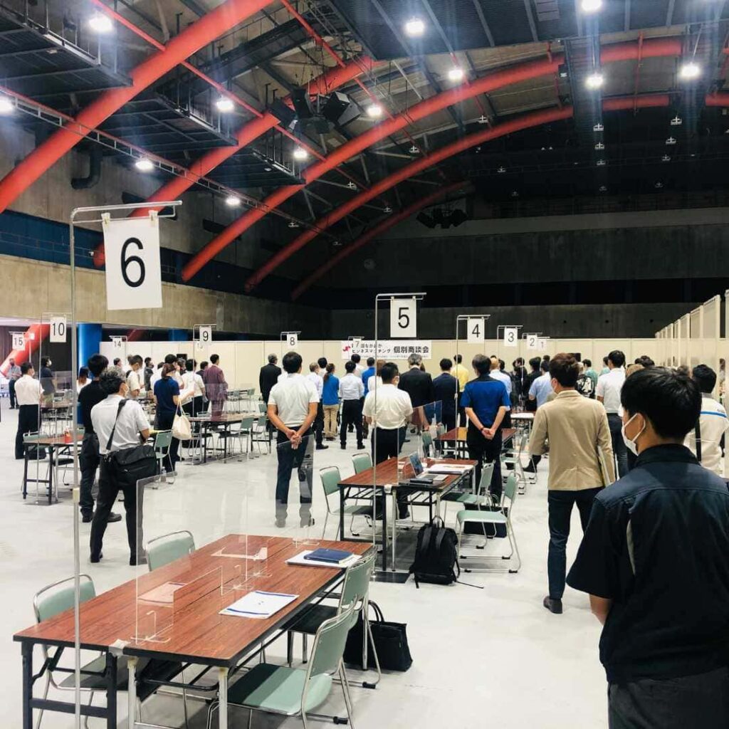 番号札の付いた机が並ぶ屋内の会場