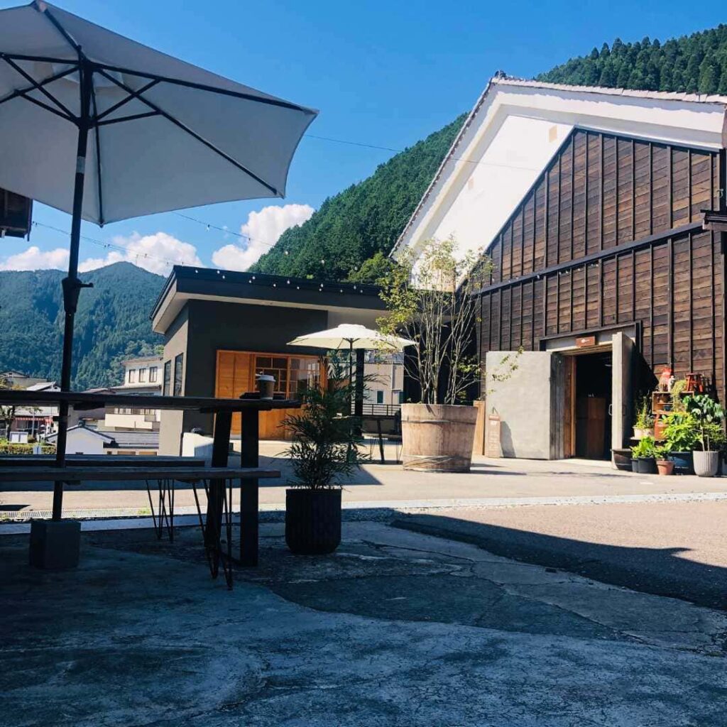 山あいに建つ木造の建物と、パラソルのある中庭
