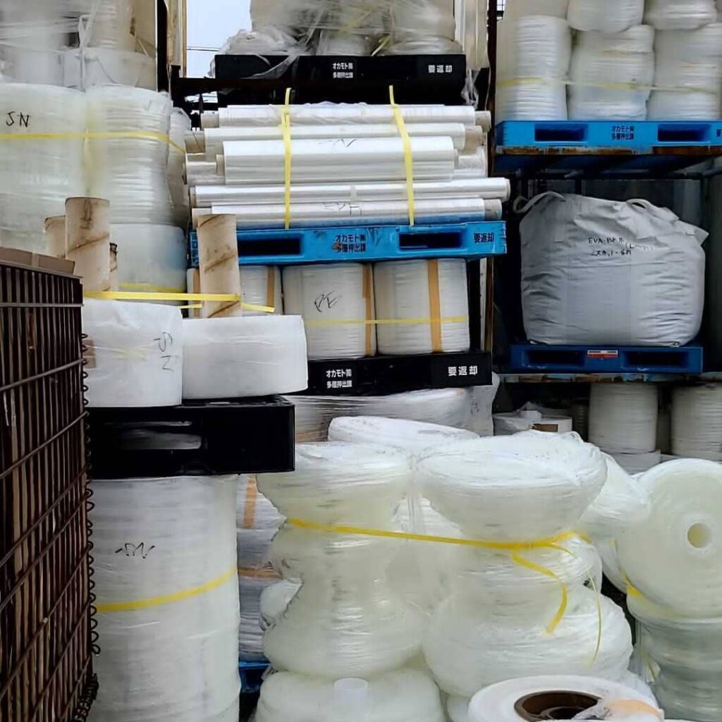 倉庫に積まれたプラスチックのロールとフレコンバッグ